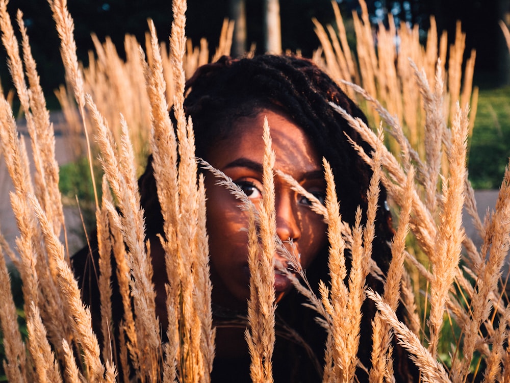 a woman with dreadlocks standing in a field of tall grass