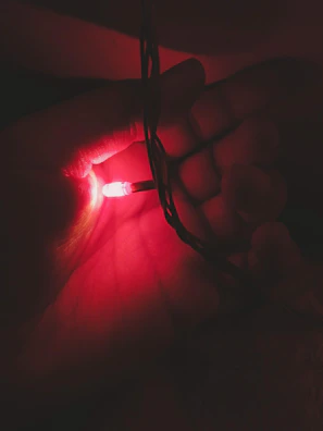 Close-up of hands gently holding a glowing wellness device with subtle gold accents.