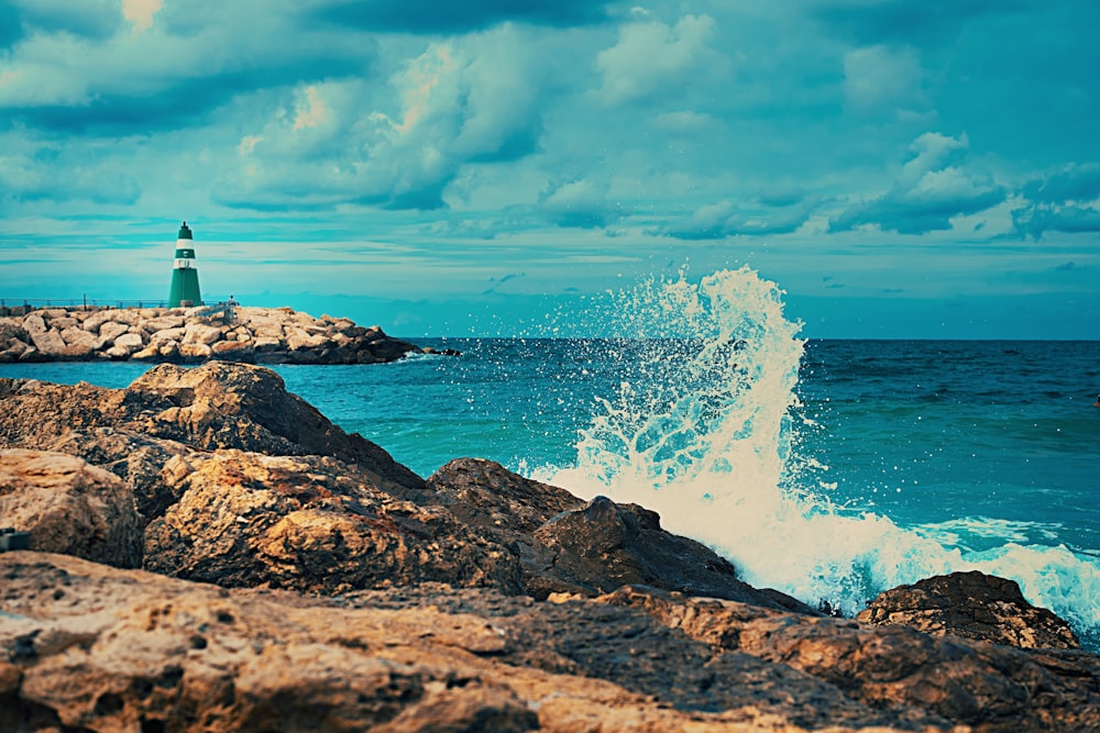 a lighthouse on top of a rocky outcropping next to the ocean