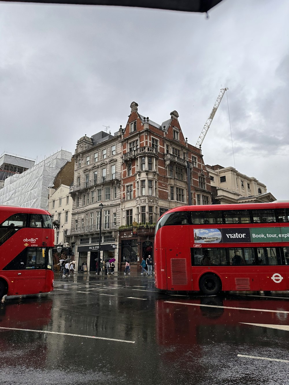 a couple of red double decker buses driving down a street