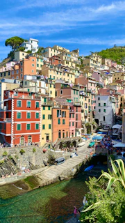 A vibrant coastal village in the Aeolian Islands glowing in warm afternoon light, with sailboats bobbing in the harbor.