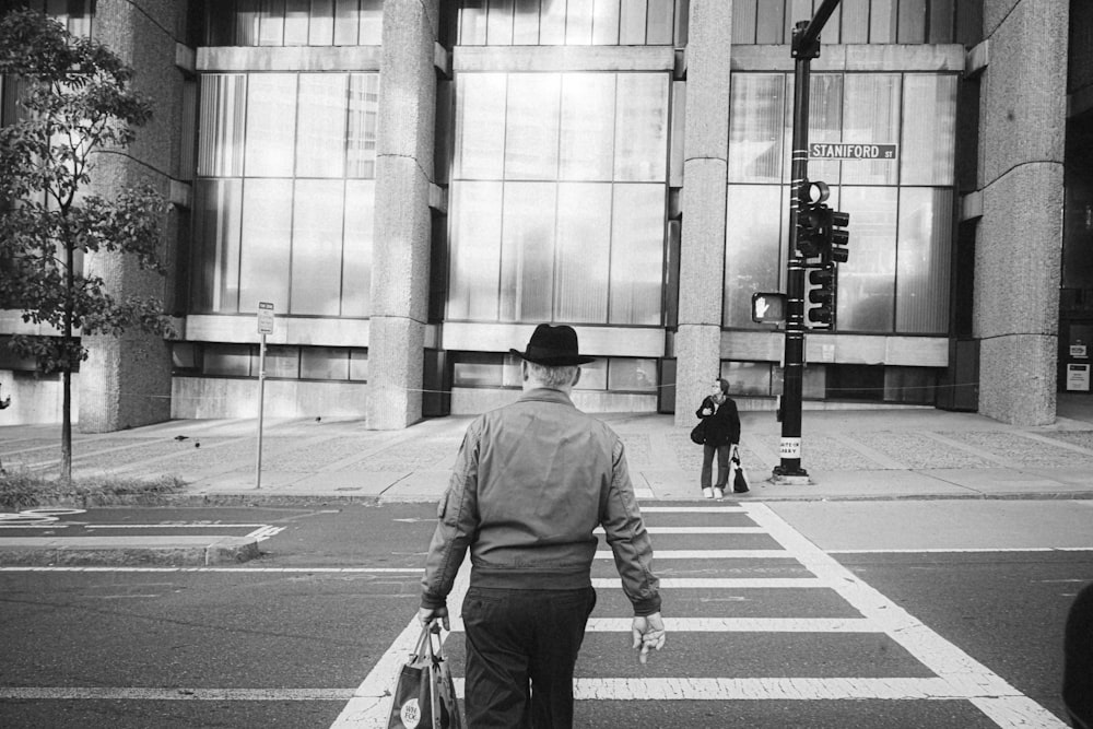 um homem caminhando por uma faixa de pedestres em frente a um prédio alto