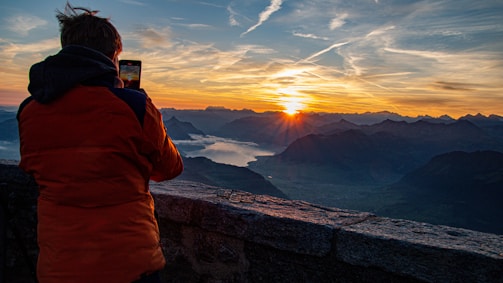 A travel influencer capturing a sunrise over a serene mountain lake.