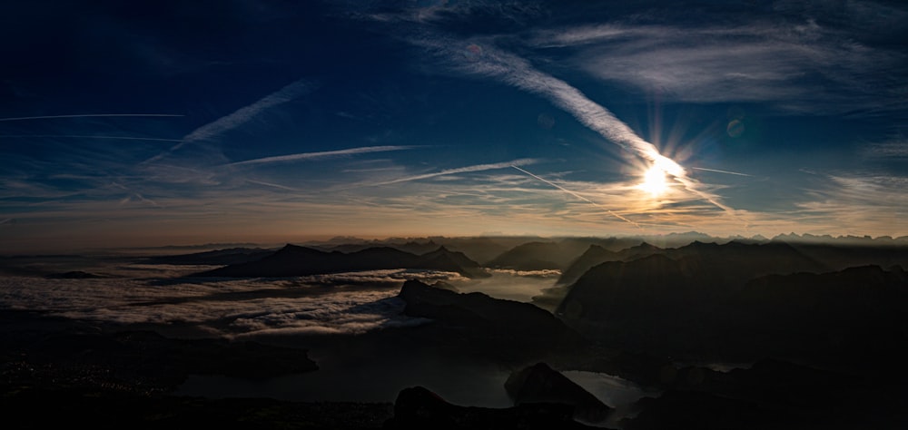 the sun is setting over the clouds and mountains