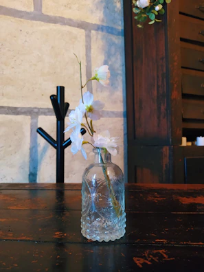 Elegant glass vase holding fresh wildflowers placed on a rustic wooden table.