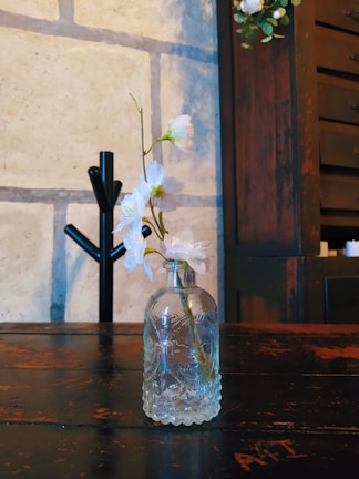 A delicate ceramic vase holding fresh wildflowers on a rustic wooden table.
