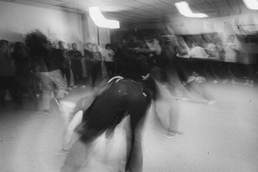 A vintage black-and-white photo of dancers mid-swing in a lively New York City ballroom.