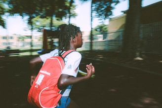 An athlete wearing a sleek sports backpack while jogging through a park.