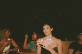 A softly lit intimate gathering with members engaged in quiet conversation over drinks in a warm, minimalist setting.