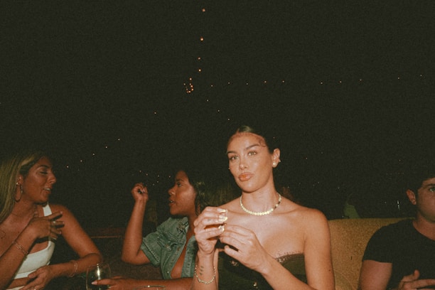 An elegant group of well-dressed members sharing a quiet conversation in a softly lit, minimalist lounge.