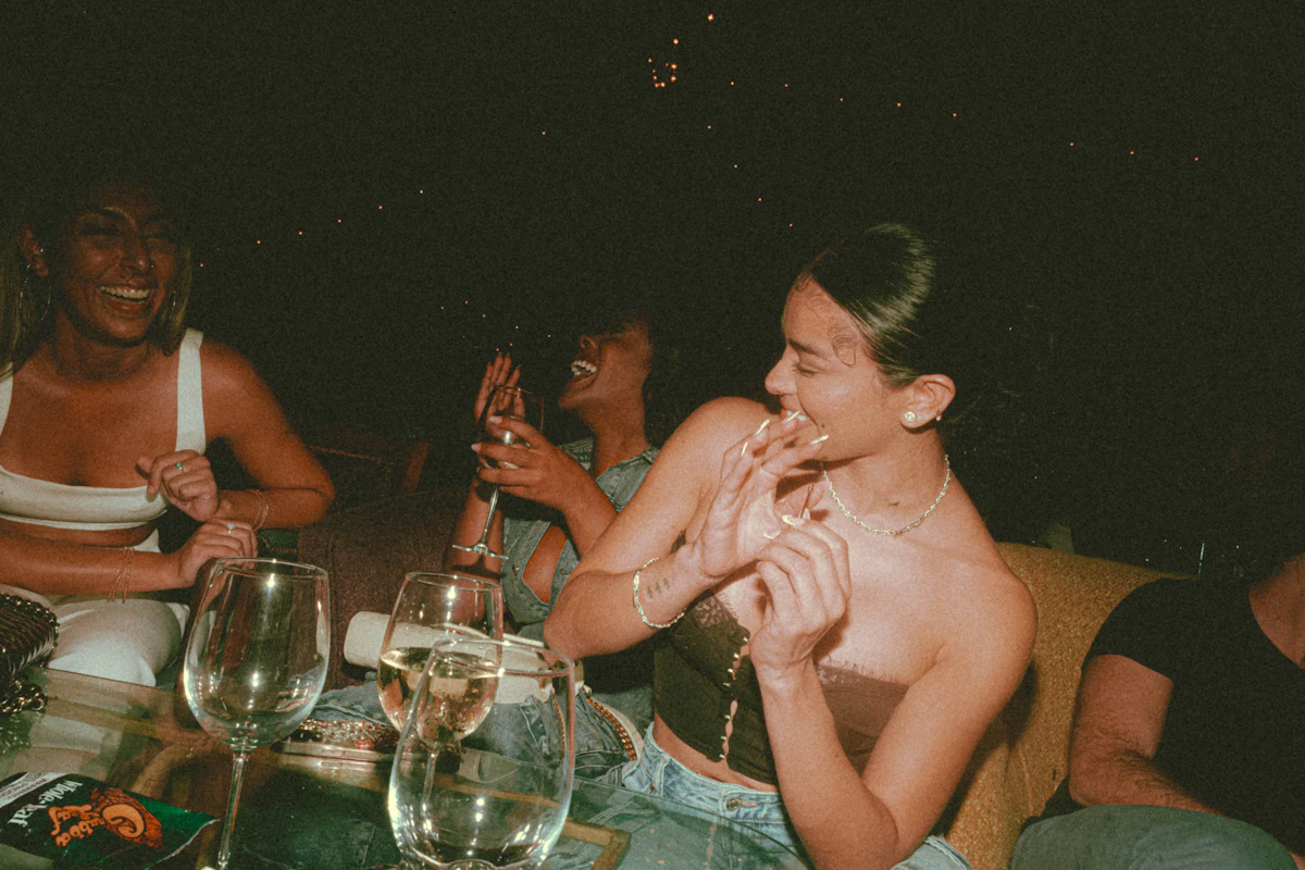 Guests laughing around a candlelit outdoor table late in the evening