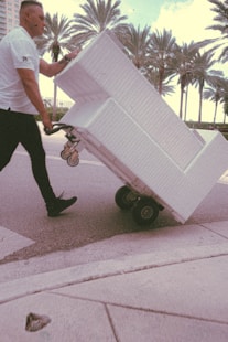 Professional movers carrying office furniture through wide building lobby.