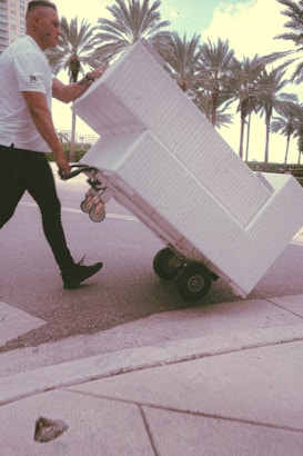 A friendly moving team carefully carrying furniture down a sunny Barcelona street.
