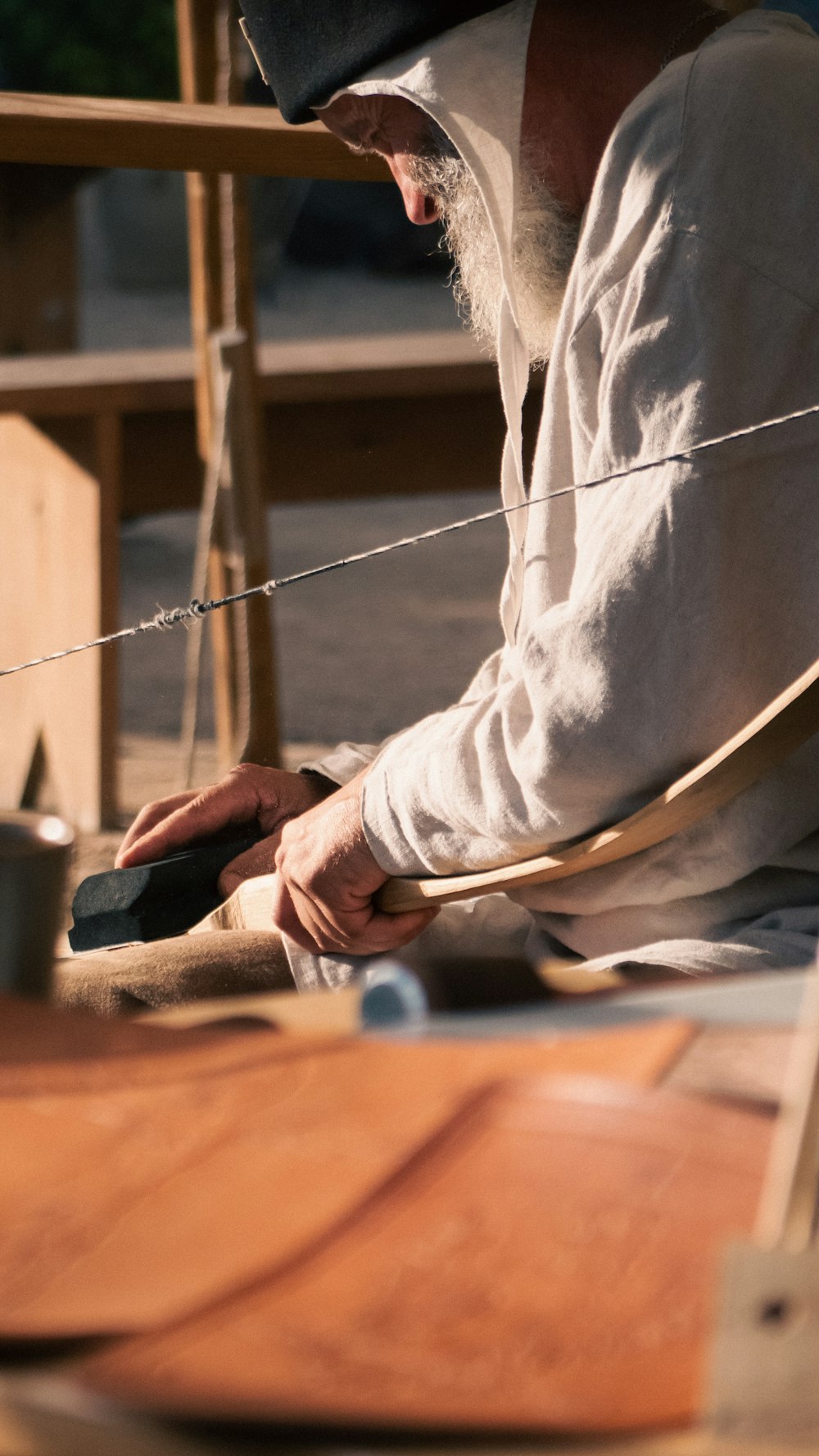 a man sitting on a bench working on a piece of wood