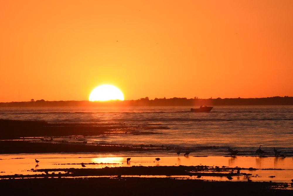 太陽が遠くにボートで海に沈んでいます