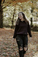 Casual chic ensemble worn by a model walking through a sunlit park with autumn leaves.
