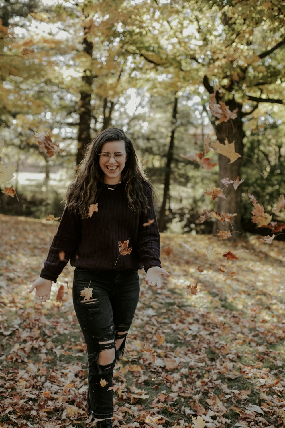 a woman walking through a leaf covered forest