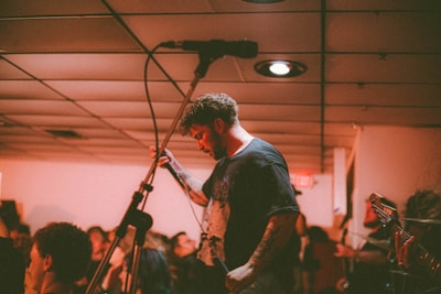 A lively comedian on stage with a microphone, engaging a small, intimate audience.