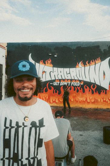 A smiling person wearing a vibrant custom printed t-shirt featuring a bold, colorful logo.