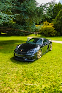 A vibrant gold car wrap being applied smoothly on a black sports car.