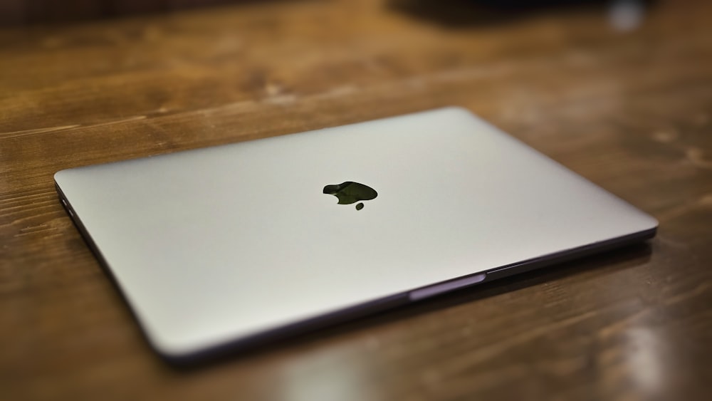 an apple laptop sitting on top of a wooden table