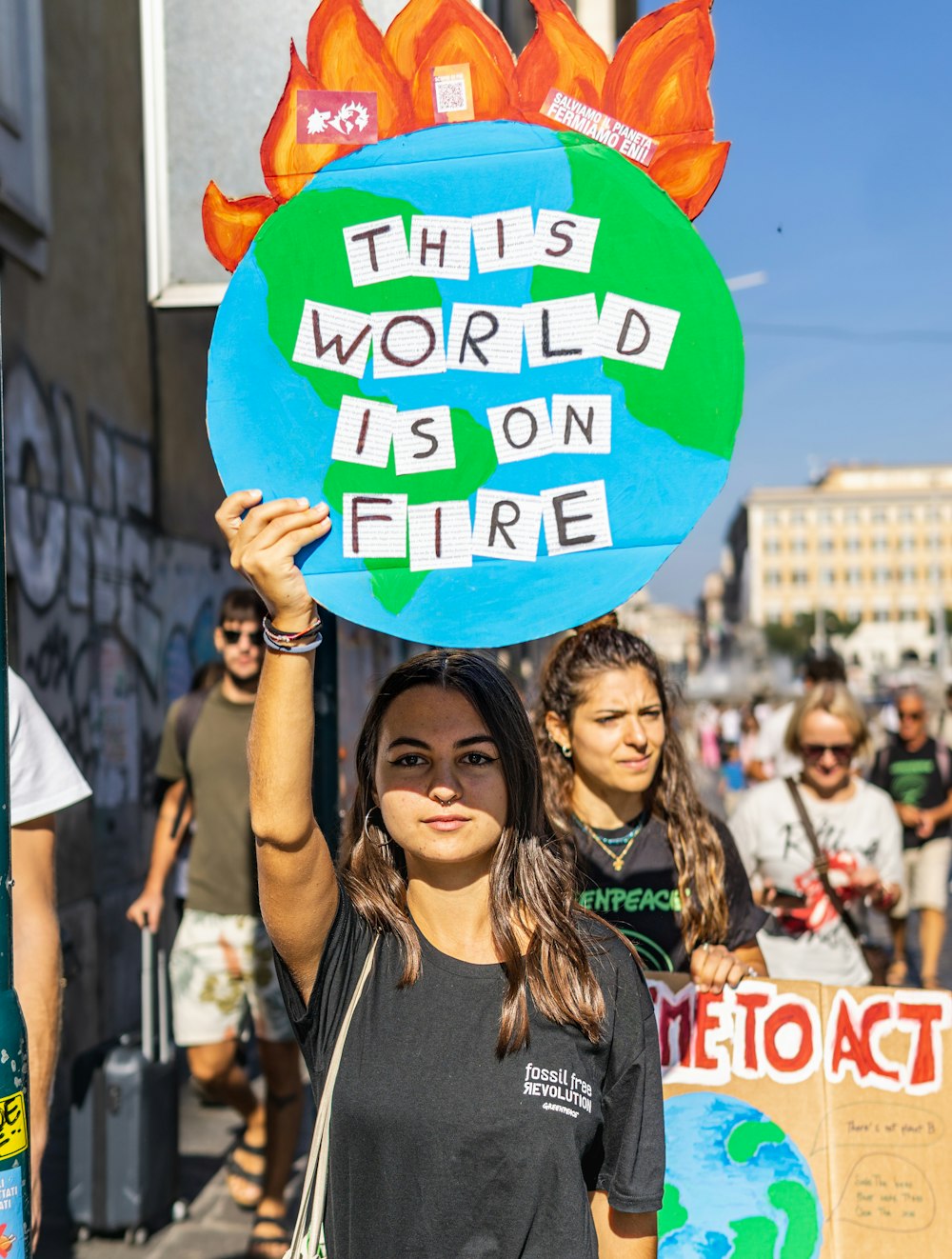 a woman holding a sign that says this world is on fire