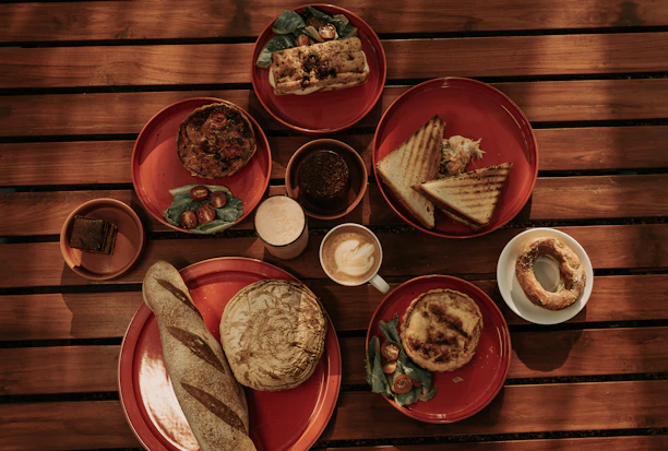 A rustic wooden table with a variety of freshly made sandwiches and traditional breakfast items.