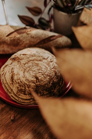 A warm, rustic loaf of bread on a wooden table with a cozy kitchen background