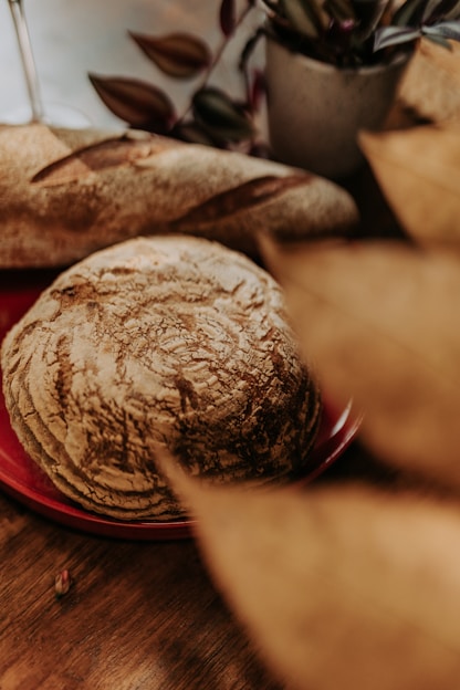 A warm, rustic loaf of bread on a wooden table with a cozy kitchen background