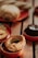 A variety of baked goods, including a round pastry with a golden crust and green filling, arranged on small, red ceramic dishes. In the background, the out-of-focus bread and a chocolate dessert add to the warm atmosphere.