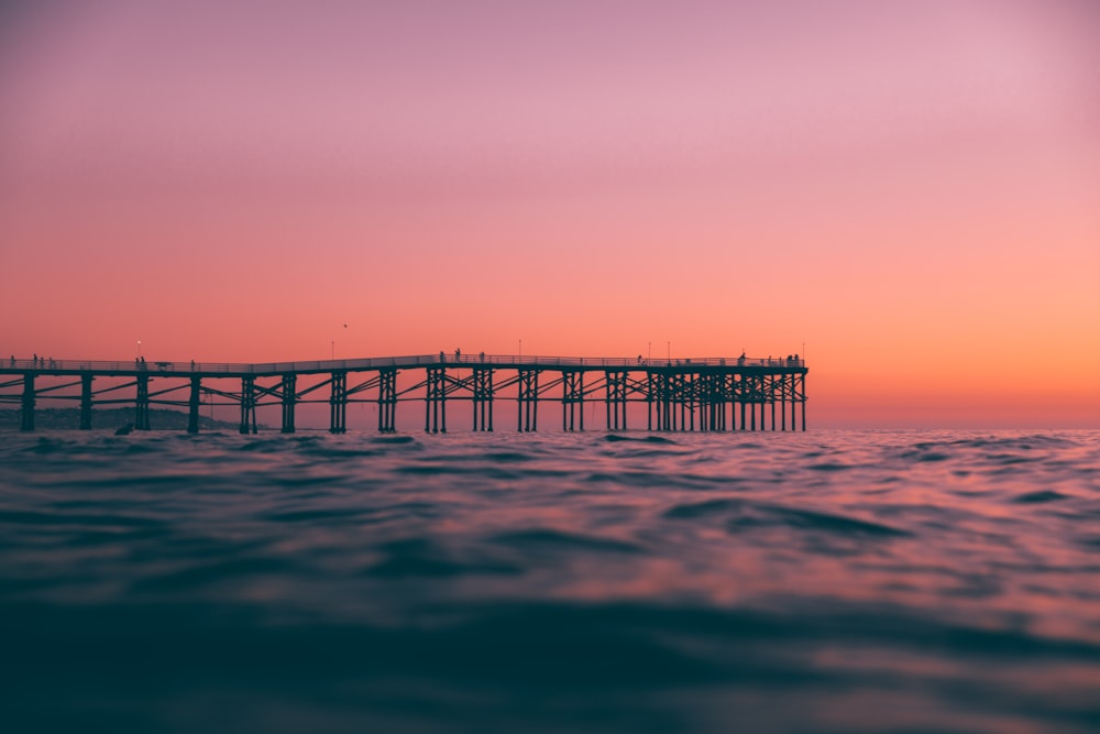 a pier in the middle of the ocean at sunset