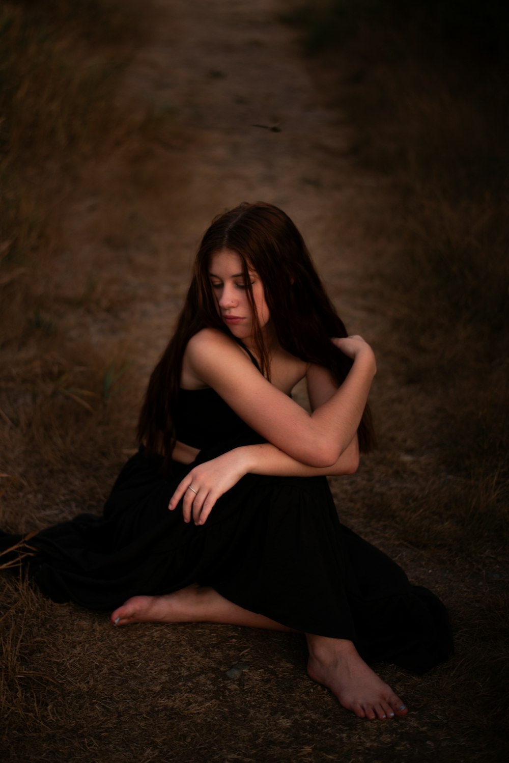 a woman in a black dress sitting on the ground