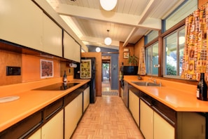 A contemporary kitchen with orange cabinetry complemented by tamota red backsplash tiles.