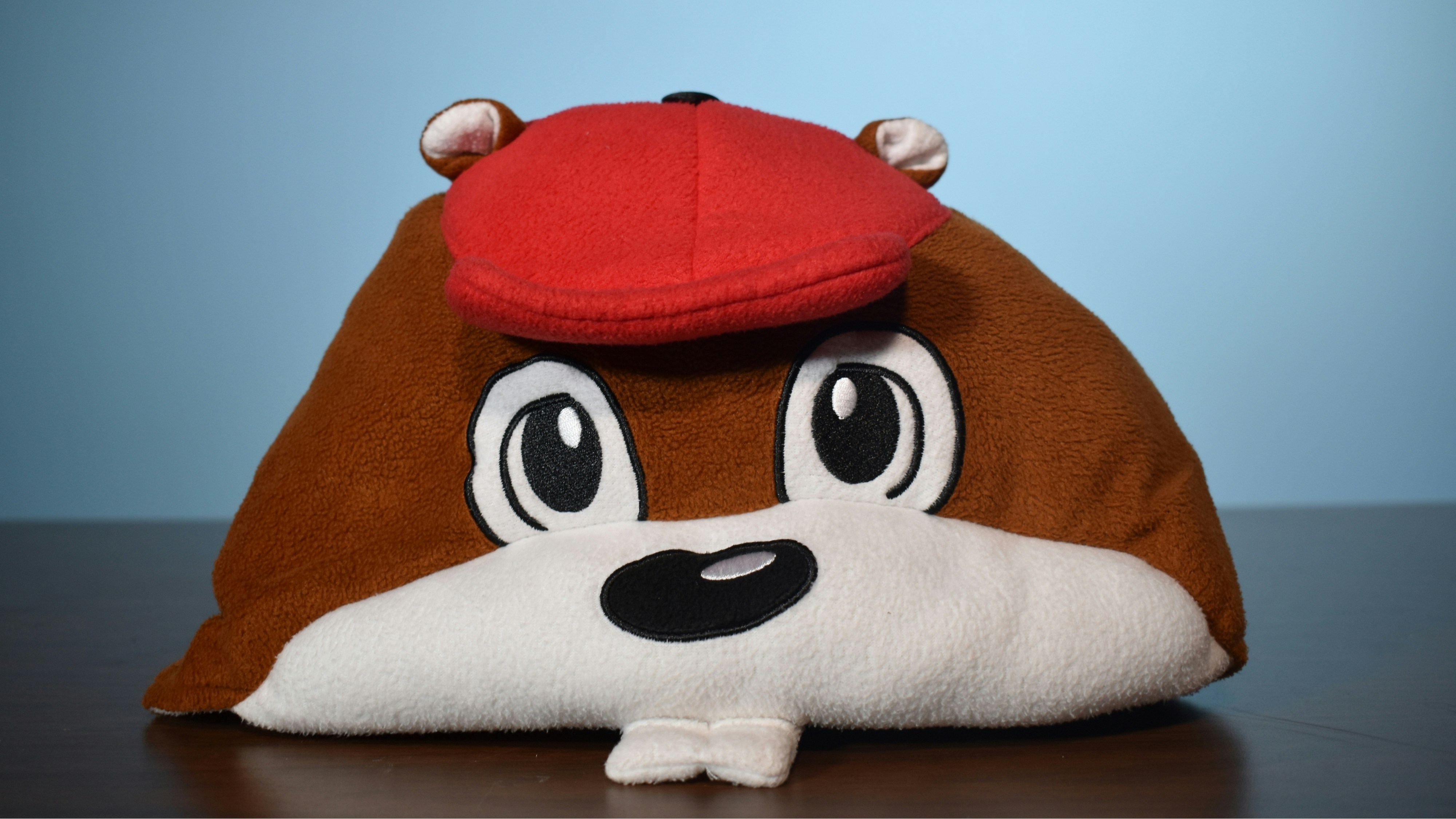 a brown and white stuffed animal with a red hat