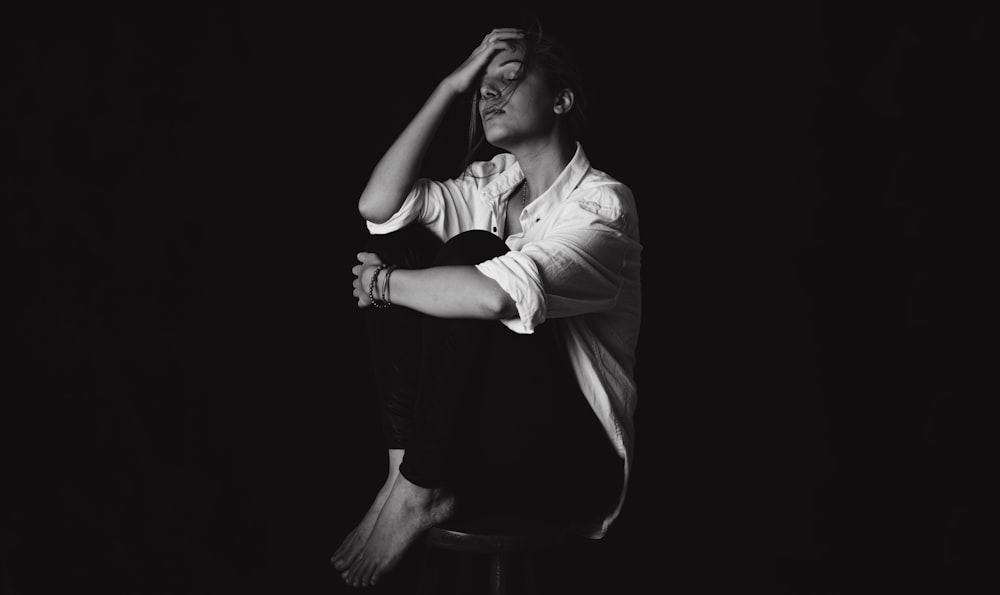 a black and white photo of a man sitting on a stool