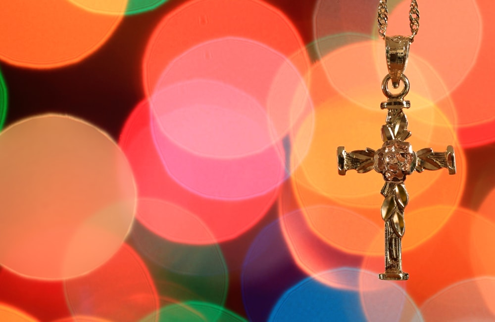 a cross on a chain in front of a colorful background