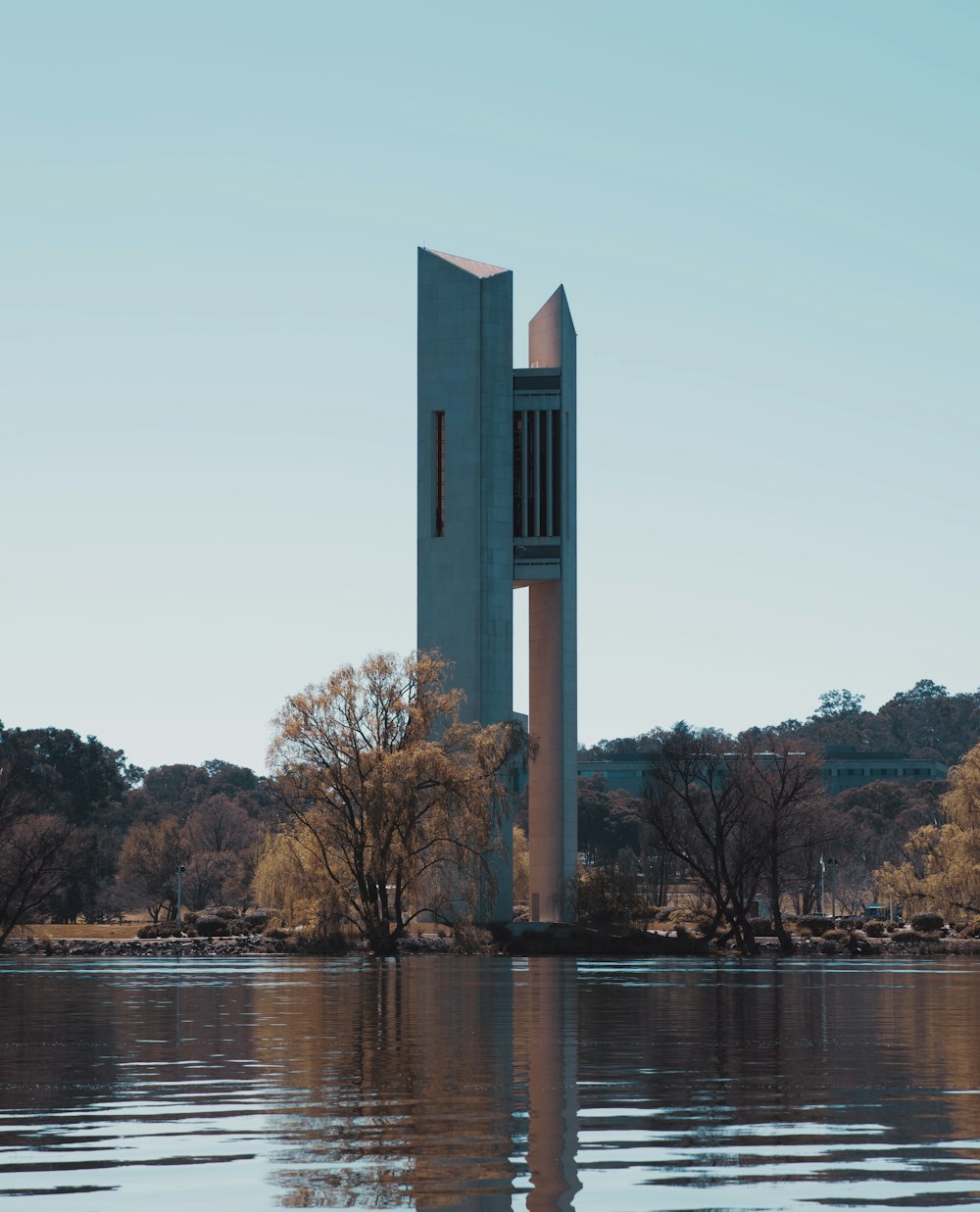 a tall tower sitting on top of a lake next to a forest