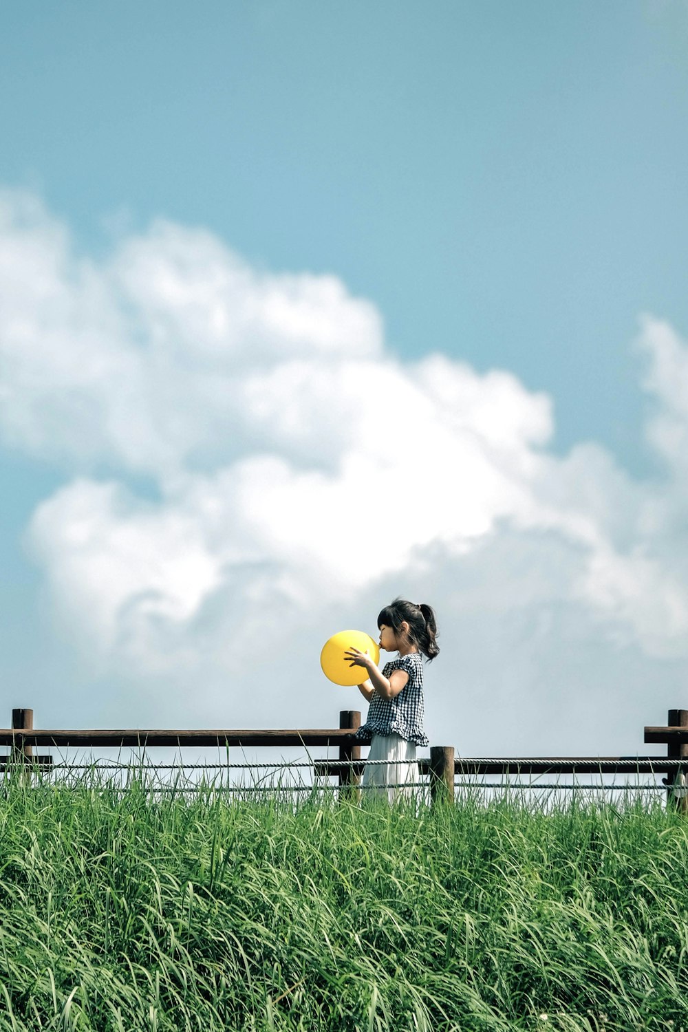 a woman holding a frisbee standing next to a lush green field