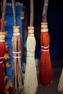 Artisan hands weaving bristles into a wooden broom handle.