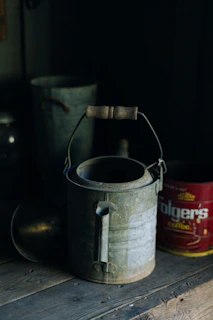 Close-up of a vintage-style metal watering can with water droplets glistening in sunlight.