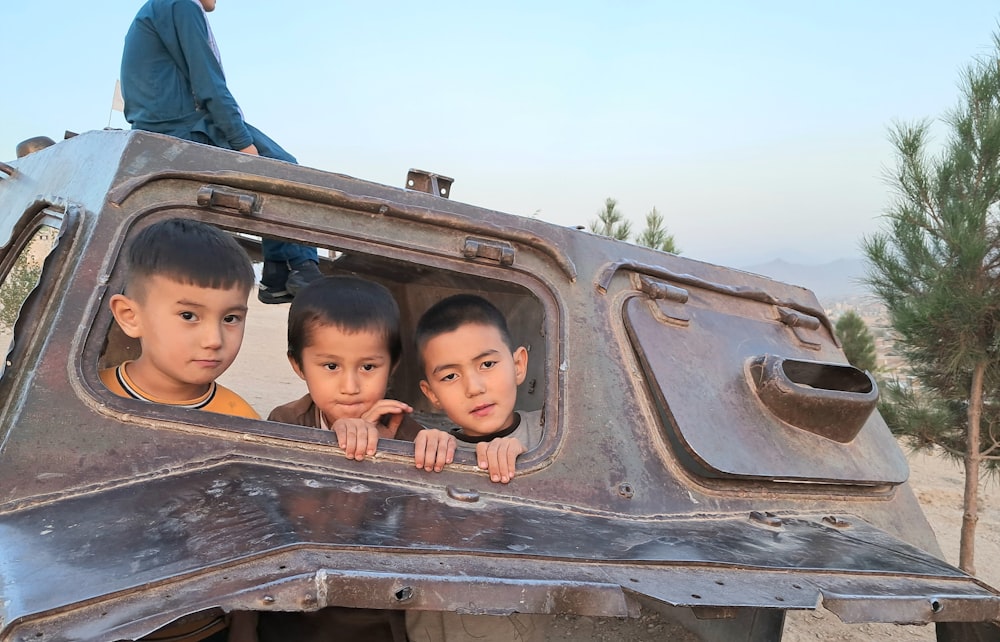 three young boys are looking out of a vehicle