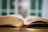 Close-up of a customer holding an open book with golden pages in warm natural light.
