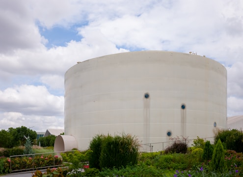a large white water tank sitting next to a lush green field