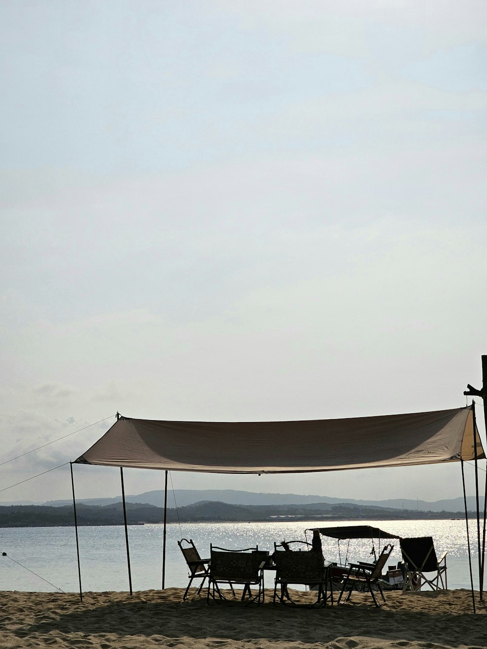 a tent set up on a beach next to a body of water