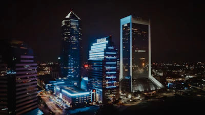 A sleek urban nightscape with deep blue and charcoal tones reflecting city lights.