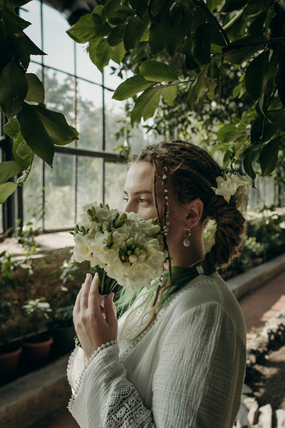 a woman holding a bunch of flowers in a greenhouse