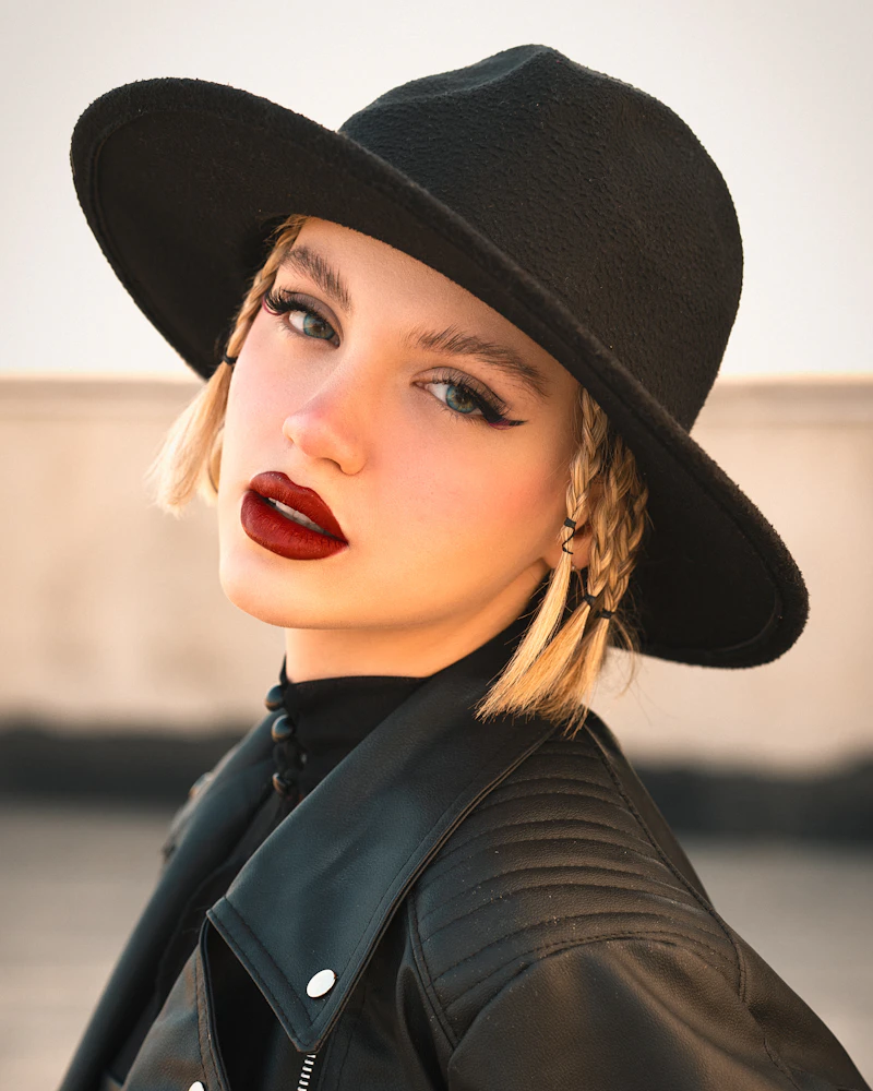 Margaux in a wide-brimmed black hat and leather jacket for the Night Coat campaign.
