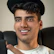 Young man smiling while watching an online psychology lecture on his laptop.