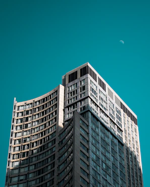 Modern high-rise building under moonlight with sleek architectural lines.