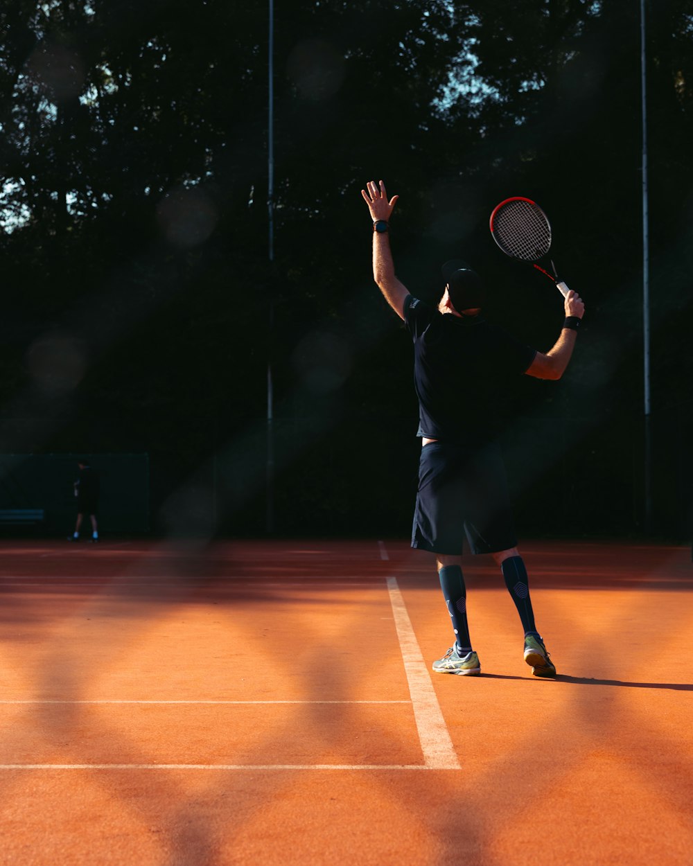 ein Mann hält einen Tennisschläger auf einem Tennisplatz